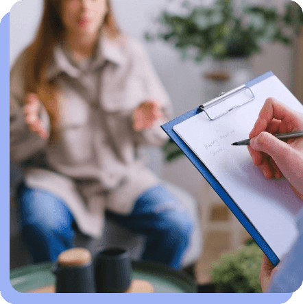Profissional de psicologia anotando observações durante uma sessão de terapia com uma cliente.